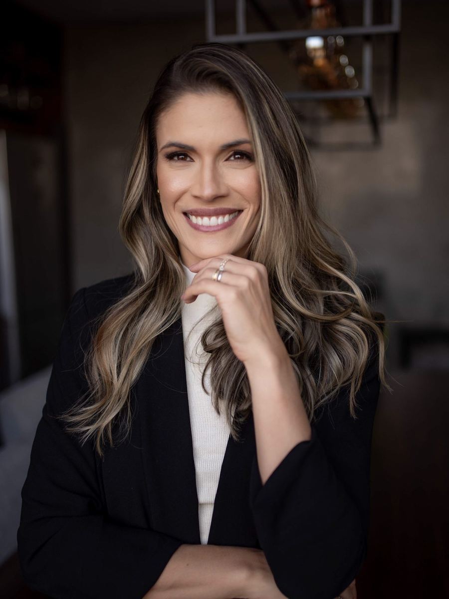 Juliana Valeriano, retrato em blazer preto e gola alta creme, olhar direto para a câmera